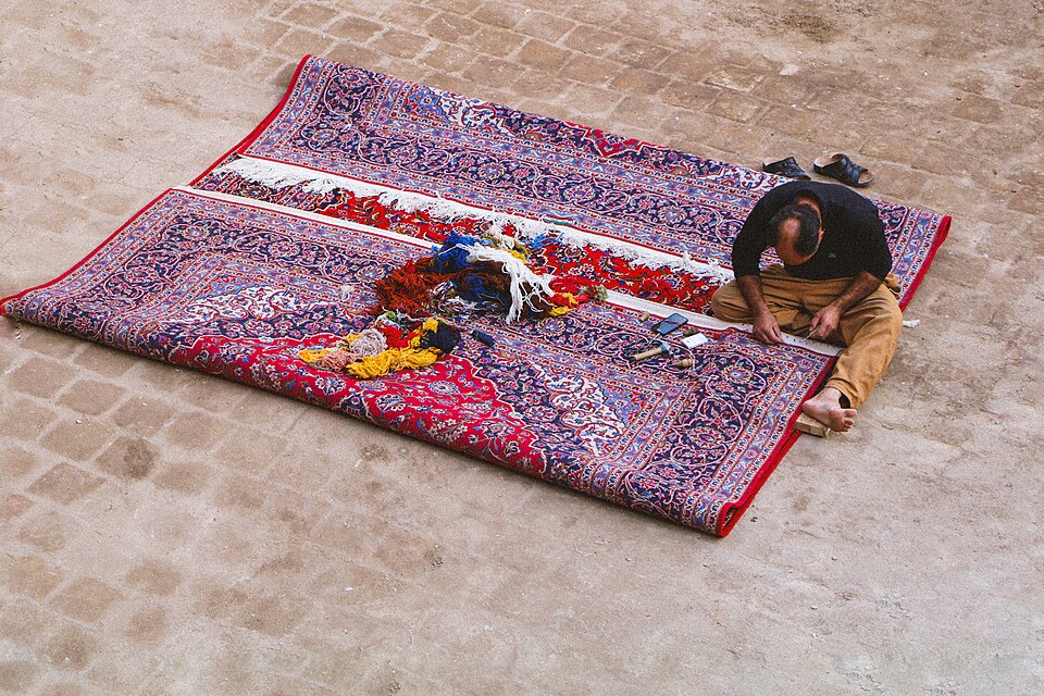 کار رفو و مرمت قالی در کاشان؛ تصویر زمینه هنر قالی، نه نمایش مرحله بافت.